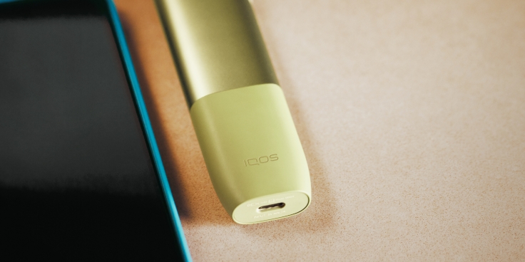IQOS ILUMA ONE device next to a mobile phone.